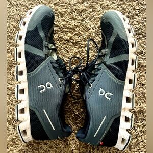 On cloud black and gray tennis shoe.